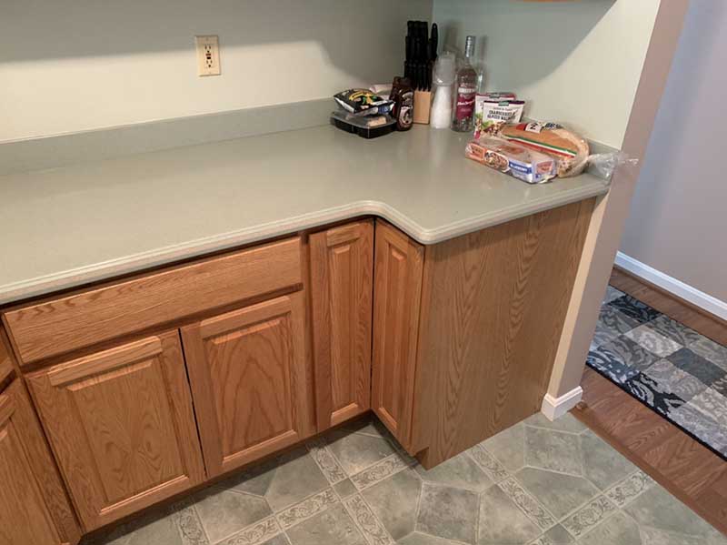 A cramped kitchen with old-fashioned, scuffed wooden cabinets