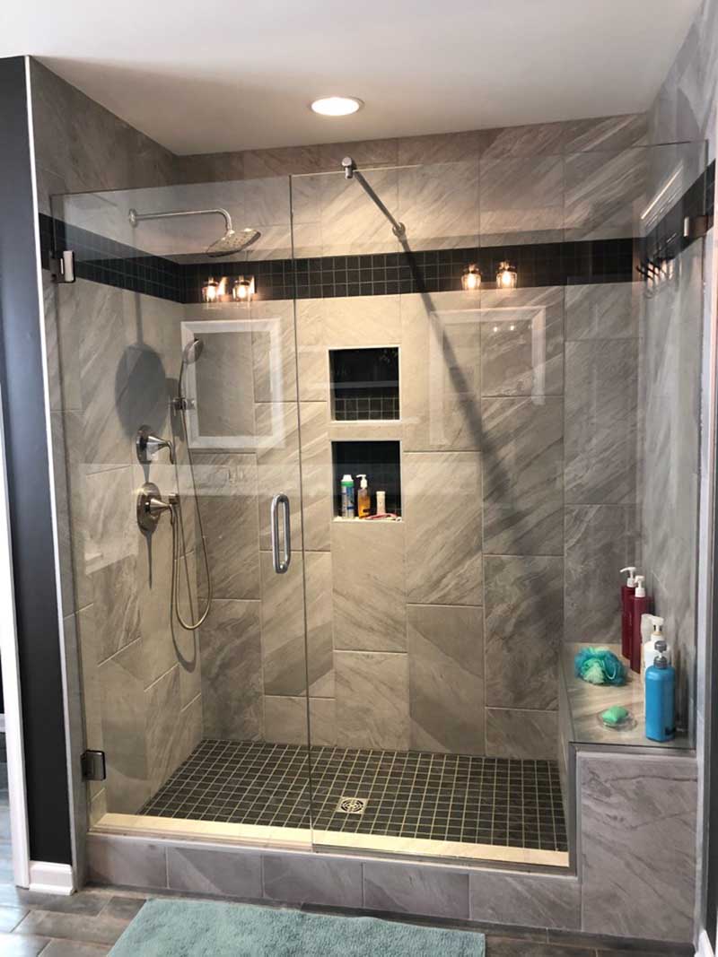 A sleek and contemporary shower with frameless glass walls and a rainfall showerhead.
