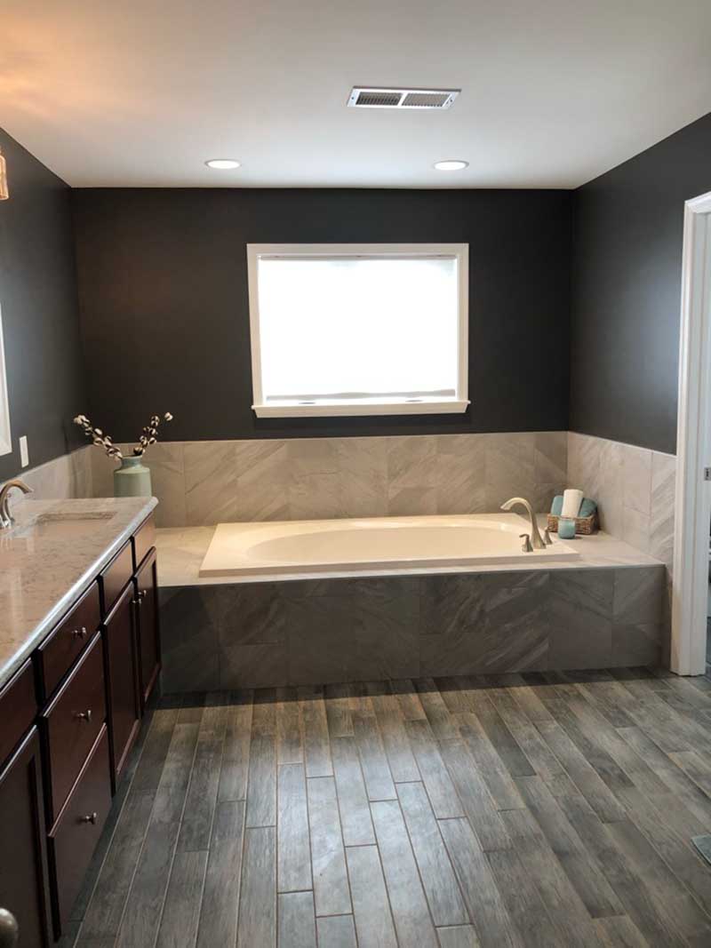 A newly renovated bath tub with wood flooring and a sunken tub.