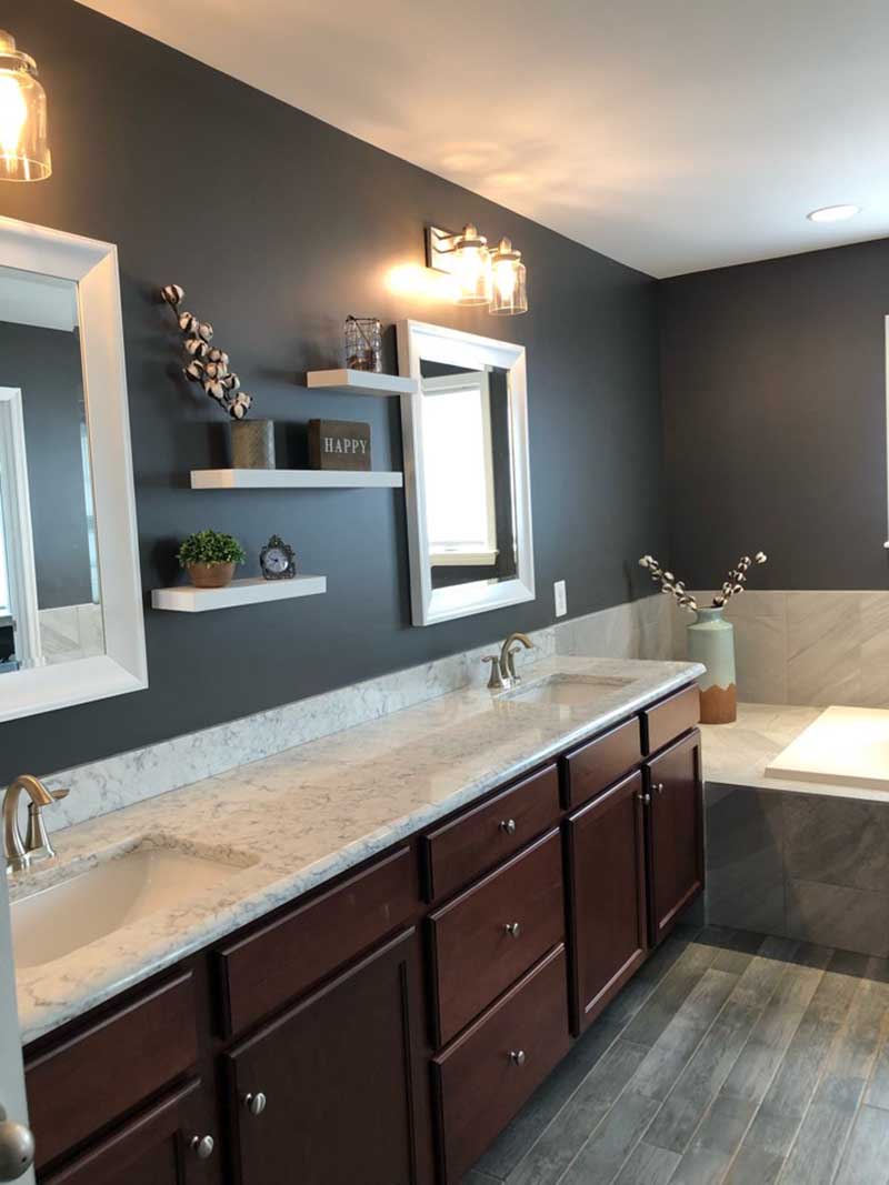 A newly remodeled master bathroom with dark brown, granite-topped cabinetry and a spacious tub.