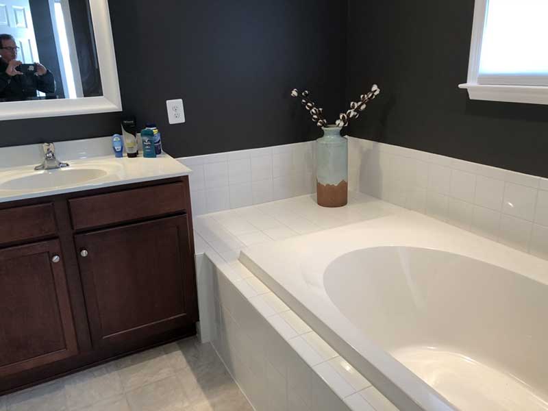 An updated bathroom with elegant design elements, including a vanity with quartz countertops, and grey tile.