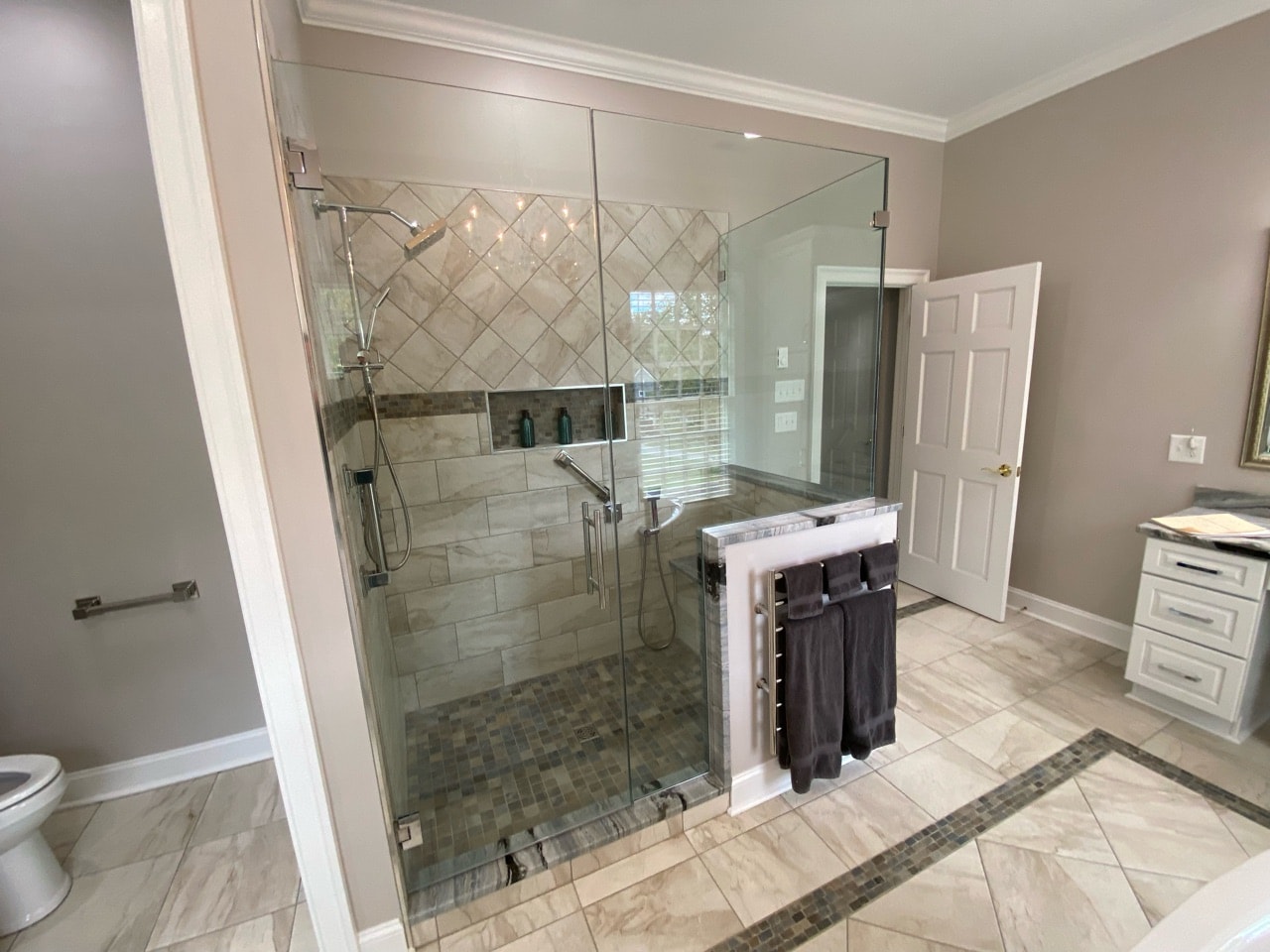 A brand-new bathroom with contemporary fixtures, a sleek glass shower enclosure, and a modern vanity with a marble countertop.